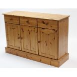 A pine sideboard fitted three frieze drawers above cupboard enclosed by three panel doors, & on