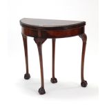 A Chippendale-style mahogany demi-lune card table inset fawn baize to the fold-over top, & on
