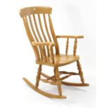 A lath-back rocking chair with hard seat, & on turned supports with turned stretchers.