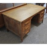 A mid-20th century oak knee-hole desk fitted with an arrangement of two brushing slides & five
