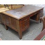An early 20th century oak knee-hole desk inset tooled brown leather cloth, fitted with an