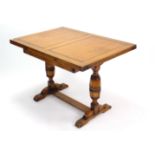 A mid-20th century oak draw-leaf dining table on bulbous-turned end supports joined by plain