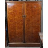 A burr-walnut finish compactum wardrobe enclosed by pair of panel doors, & on plinth base, 50”