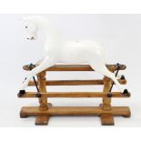 A white painted & carved wooden child’s rocking horse (lacking tail), on pine trestle base, 35” long