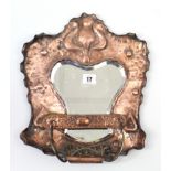 An Arts & Crafts copper frame wall mirror, inset shaped bevelled plate & with brush below, 14” x