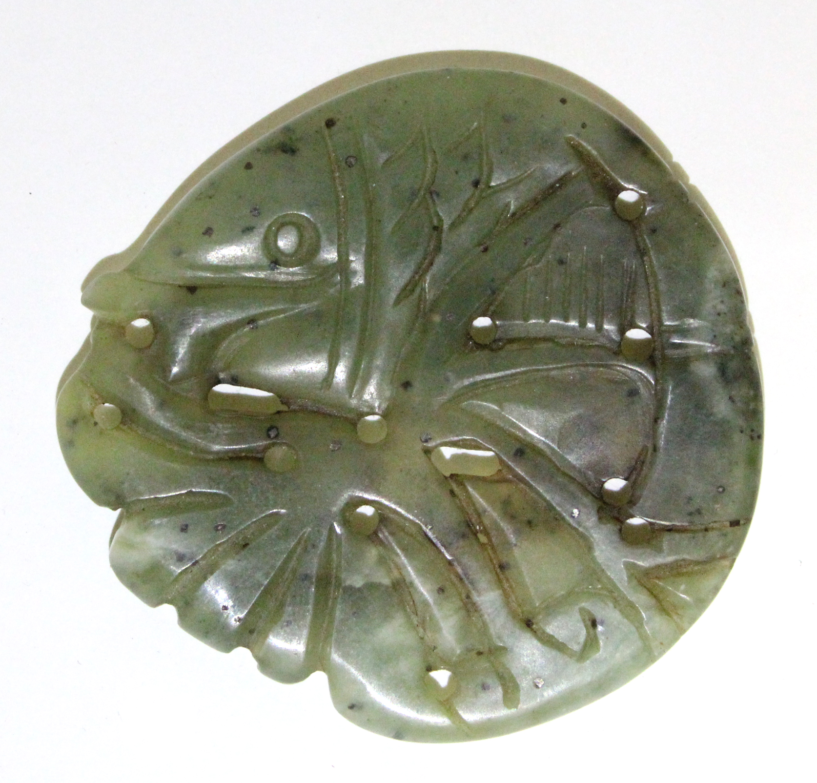 A Chinese carved & pierced jade roundel in the form of a fish amongst fronds; 2” wide.