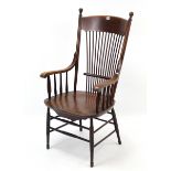 An early 20th century oak comb-back elbow chair with hard seat, & on turned tapered legs with