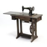 A Singer treadle sewing machine in oak case & on cast-iron base, 34” wide.