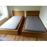 A pair of Ikea oak-finish single bedsteads complete with mattresses.