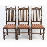 A set of three 1930’s oak dining chairs with carved top-rails, padded drop-in seats, & on bobbin