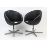 A pair of Ikea black vinyl tub-shaped easy chairs, each on silvered-metal base.