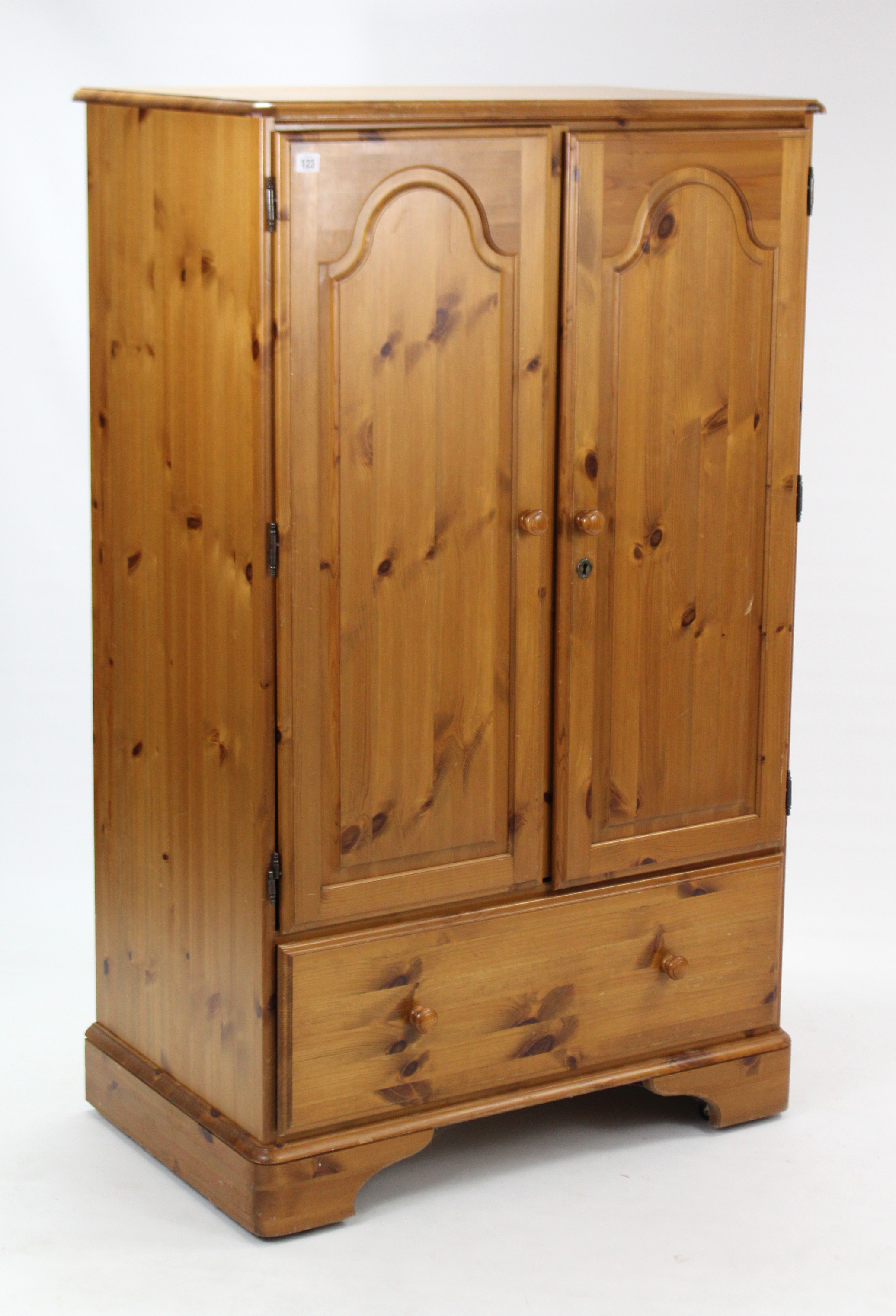 A pine nursery cupboard, enclosed by pair of fielded panel doors above a deep long drawer, & on