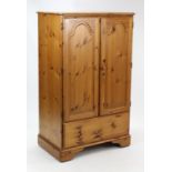 A pine nursery cupboard, enclosed by pair of fielded panel doors above a deep long drawer, & on