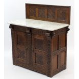 A carved oak marble-top side cabinet with low-stage panel back, & enclosed by pair of panel doors,