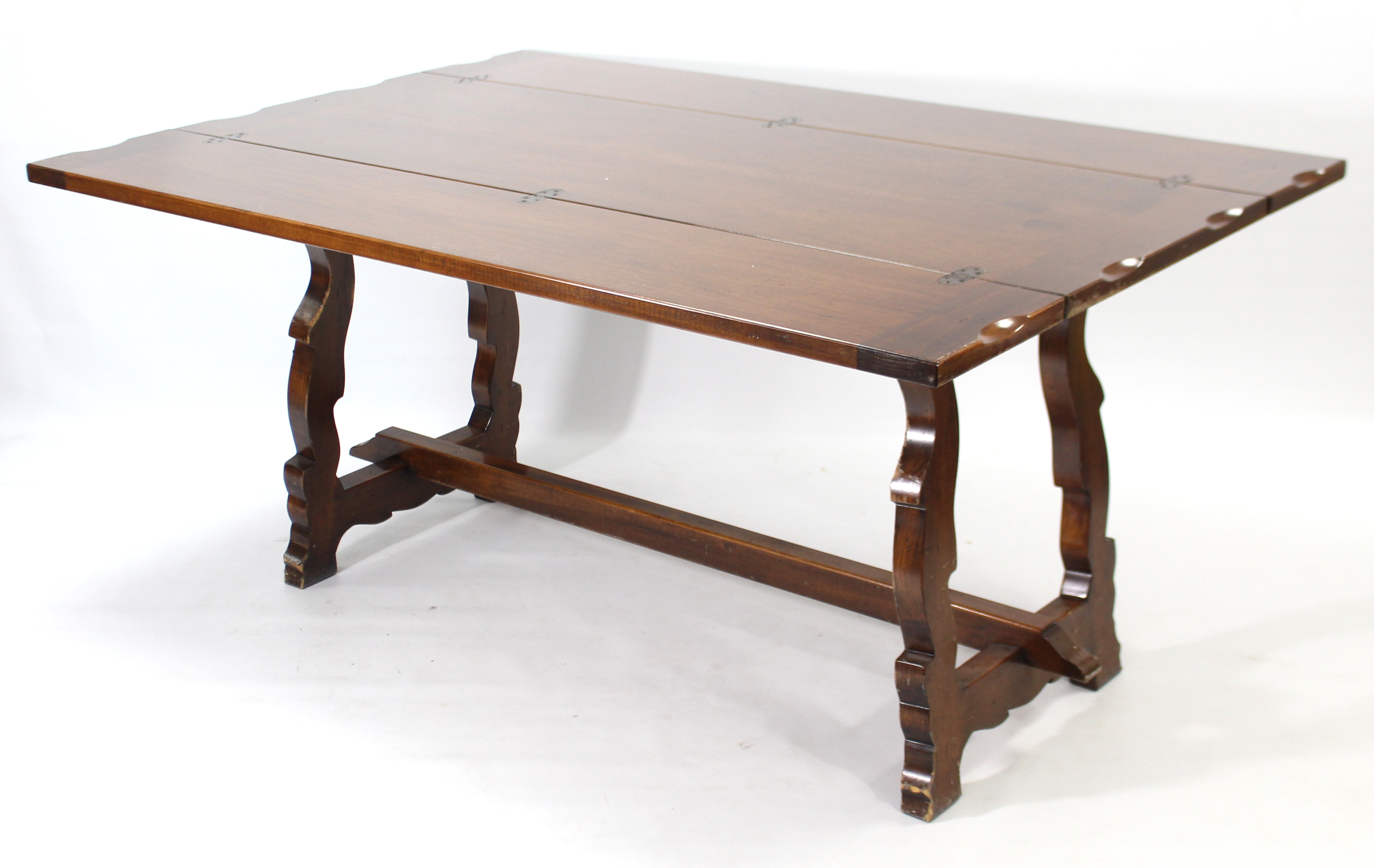 A mahogany finish dining table with rectangular fold-over top, & on shaped end supports joined by