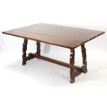 A mahogany finish dining table with rectangular fold-over top, & on shaped end supports joined by