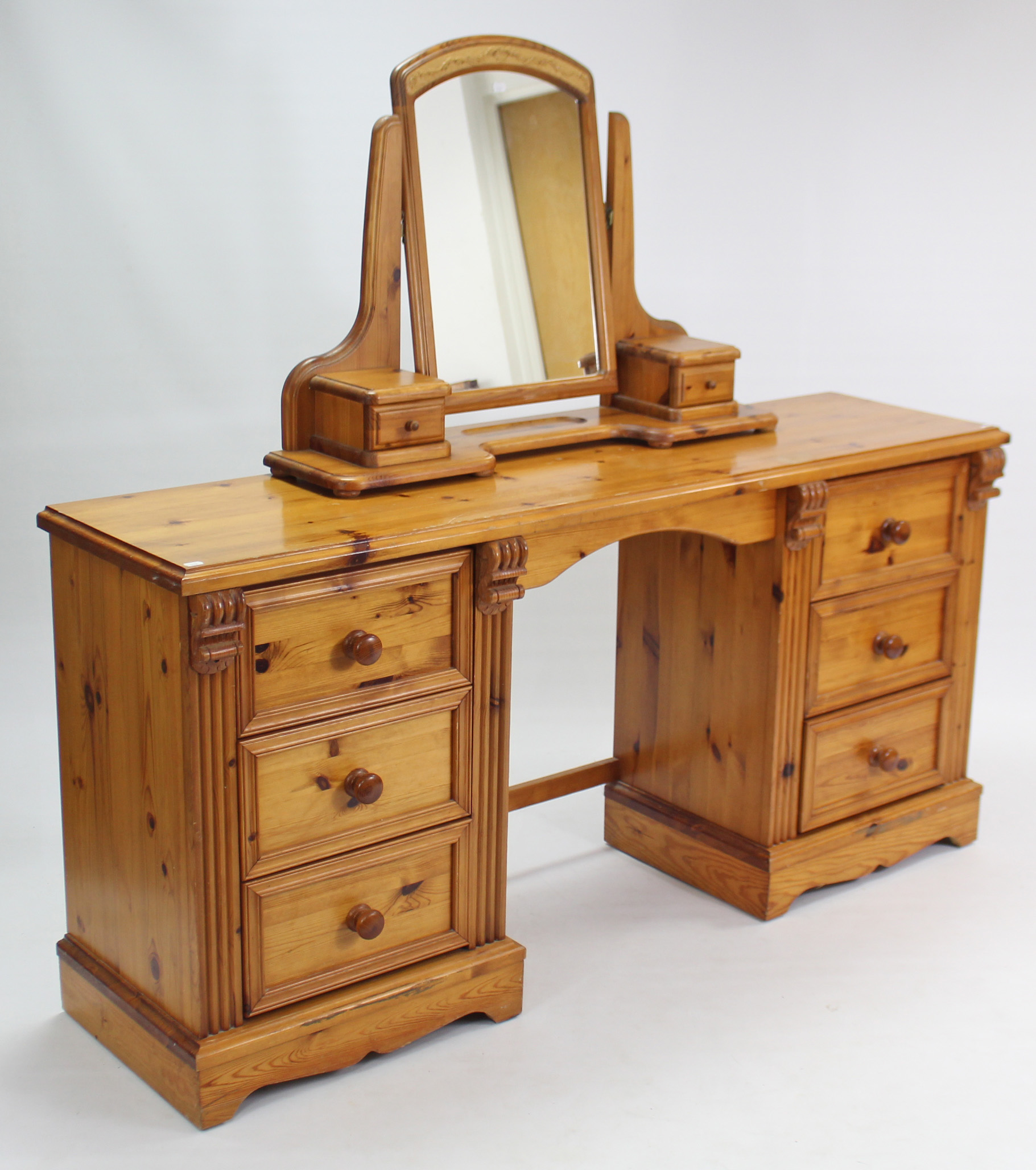 A pine kneehole dressing table, fitted three long drawers to each pedestal, on shaped plinth base,