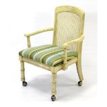 A continental-style cream painted wooden frame elbow chair inset woven cane back, with padded