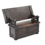 A reproduction carved oak monk’s bench with fold over top, hinged lift-seat, with panelled front &