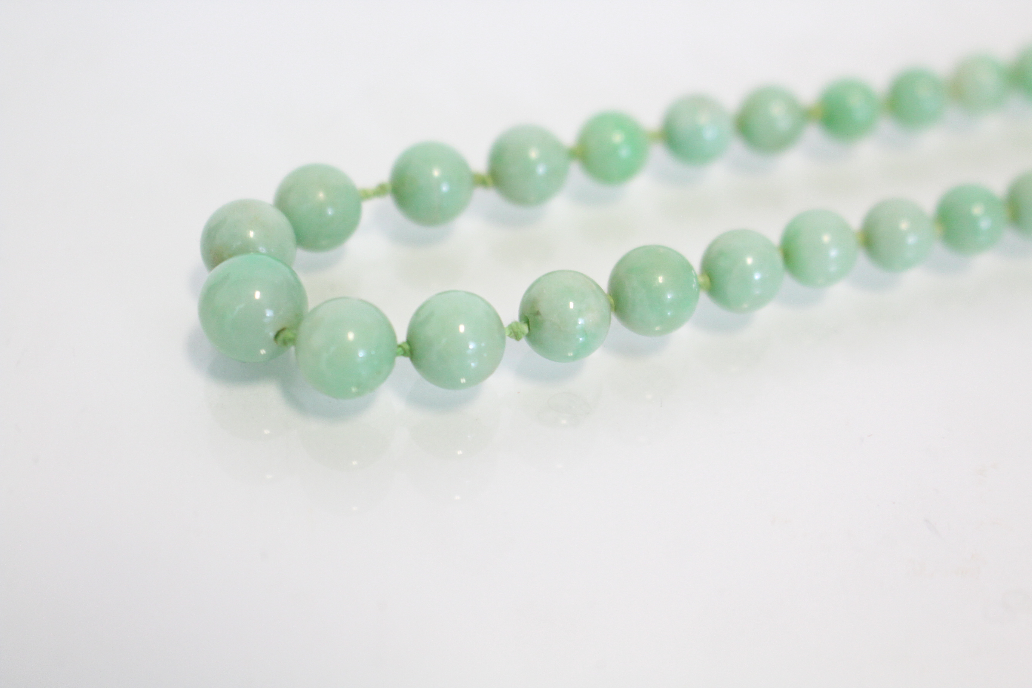 A jade necklace of pale green round graduated beads, the yellow metal pierced oval clasp marked 9ct. - Image 3 of 5
