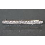 A diamond & platinum bar brooch set fifteen graduated round-cut stones, the narrow sides with