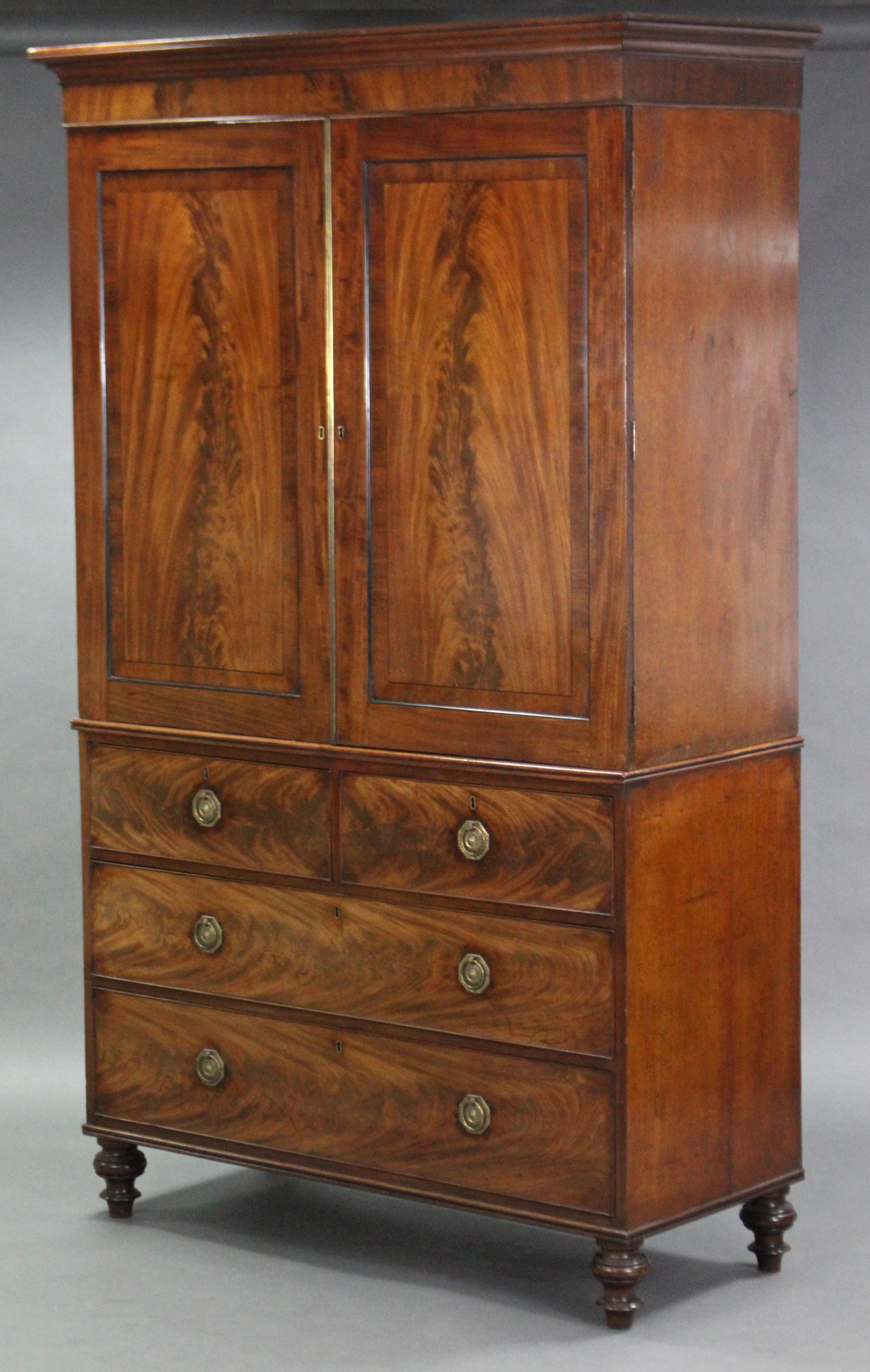 An early 19th century mahogany linen press enclosed by pair of fielded panel doors above two short