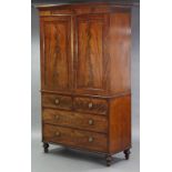 An early 19th century mahogany linen press enclosed by pair of fielded panel doors above two short
