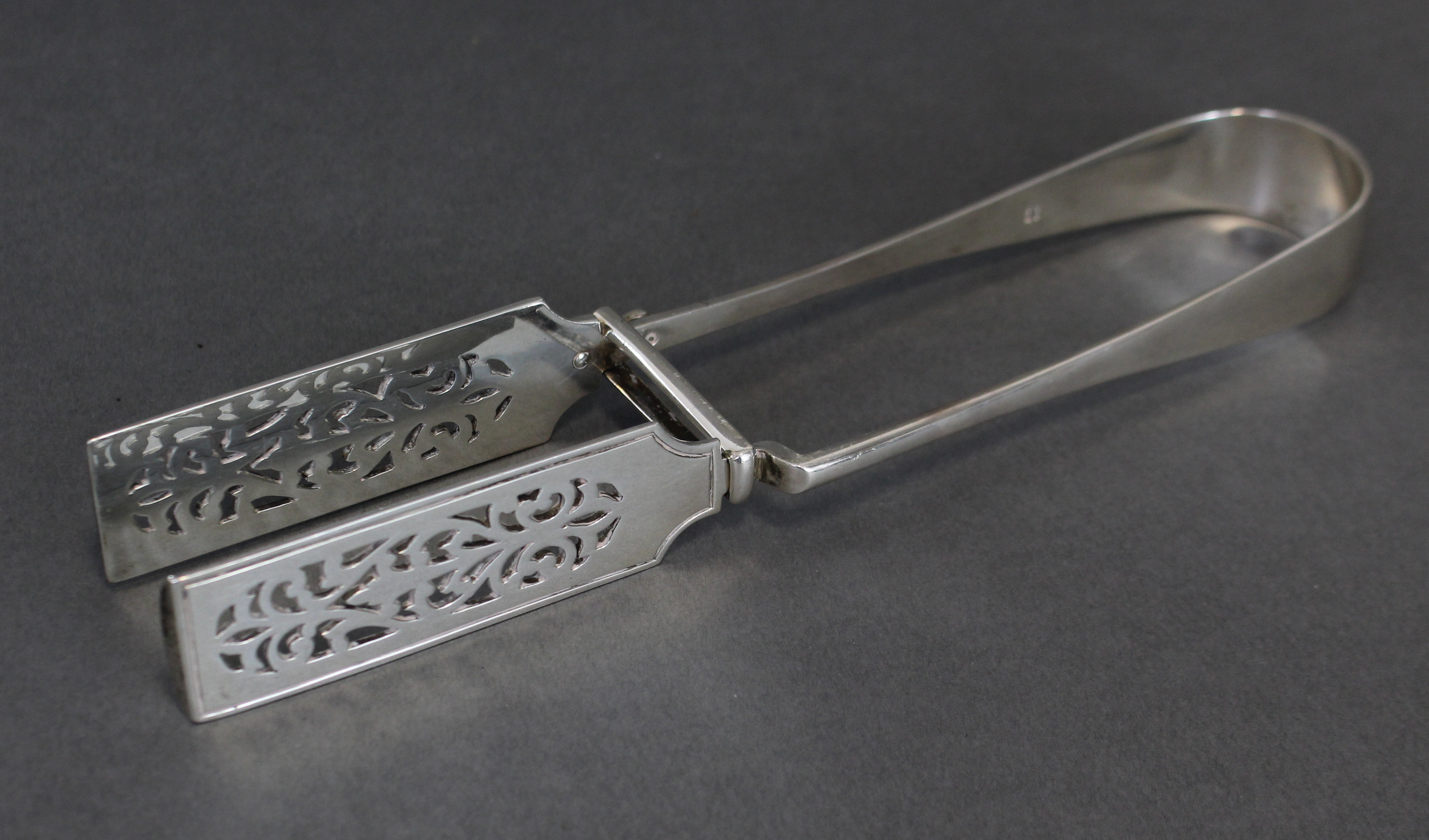 A pair of Victorian silver serving tongs with pierced rectangular blades, 10” long; London 1893,