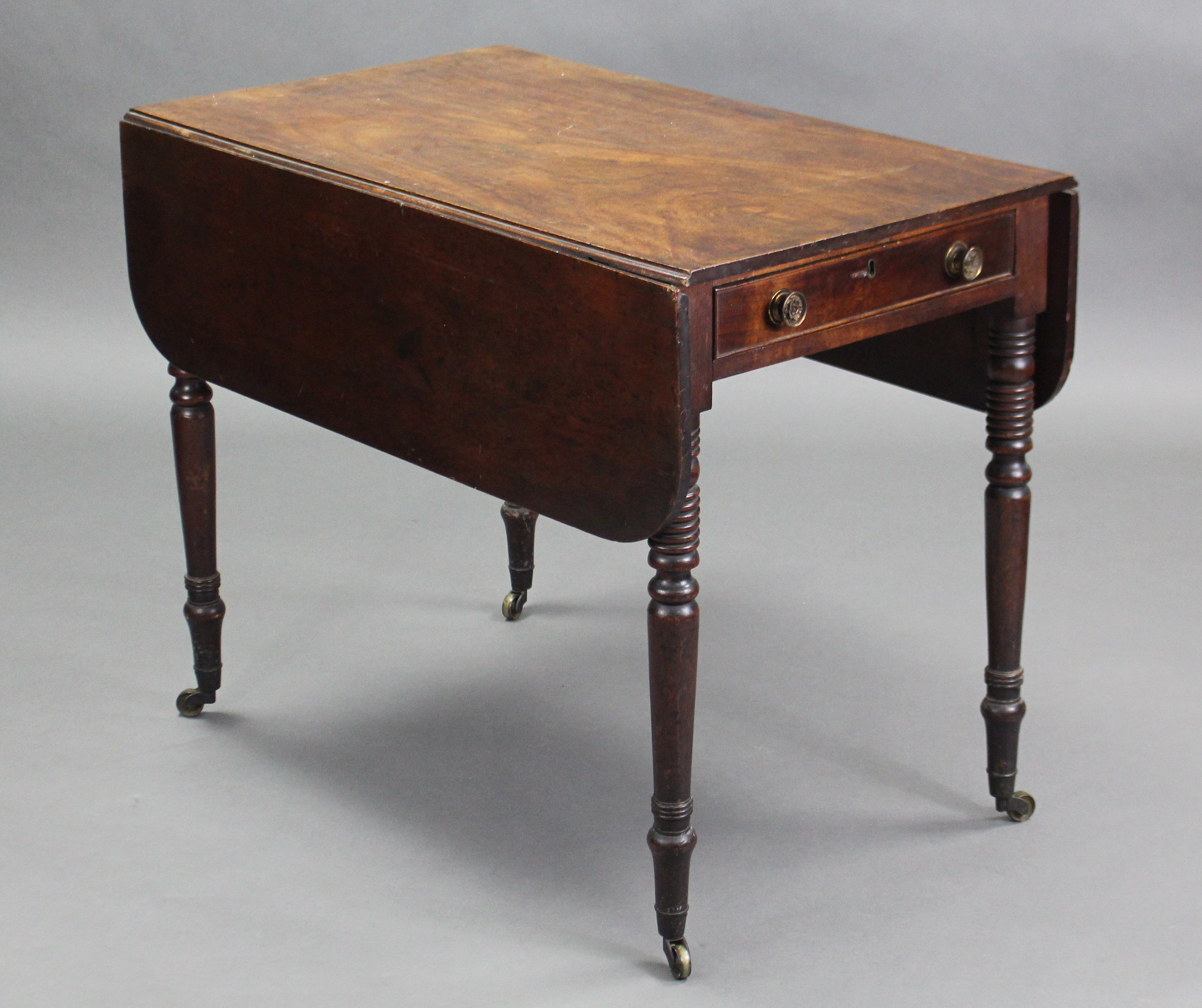 A Georgian mahogany rectangular drop-leaf table fitted drawer to one end with brass knob handles, on