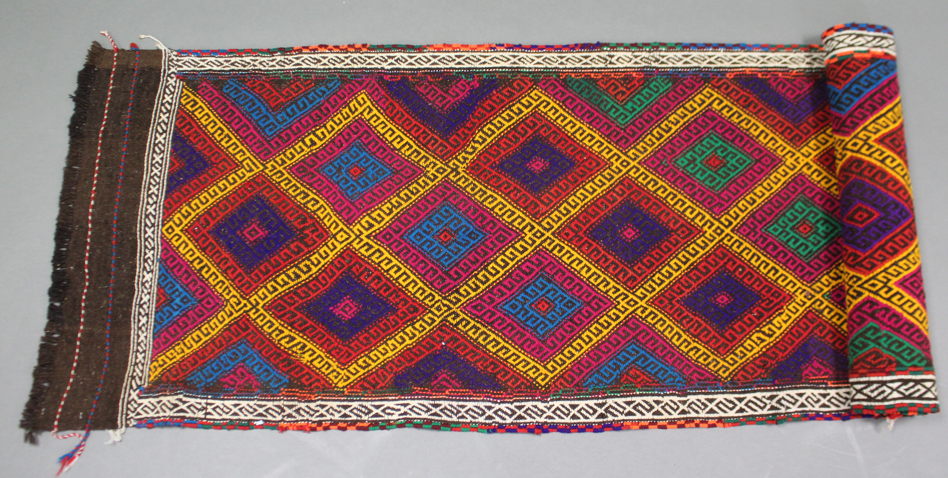 A Suzni kelim runner with multicoloured repeating lozenge motif within a narrow ivory border, 28”