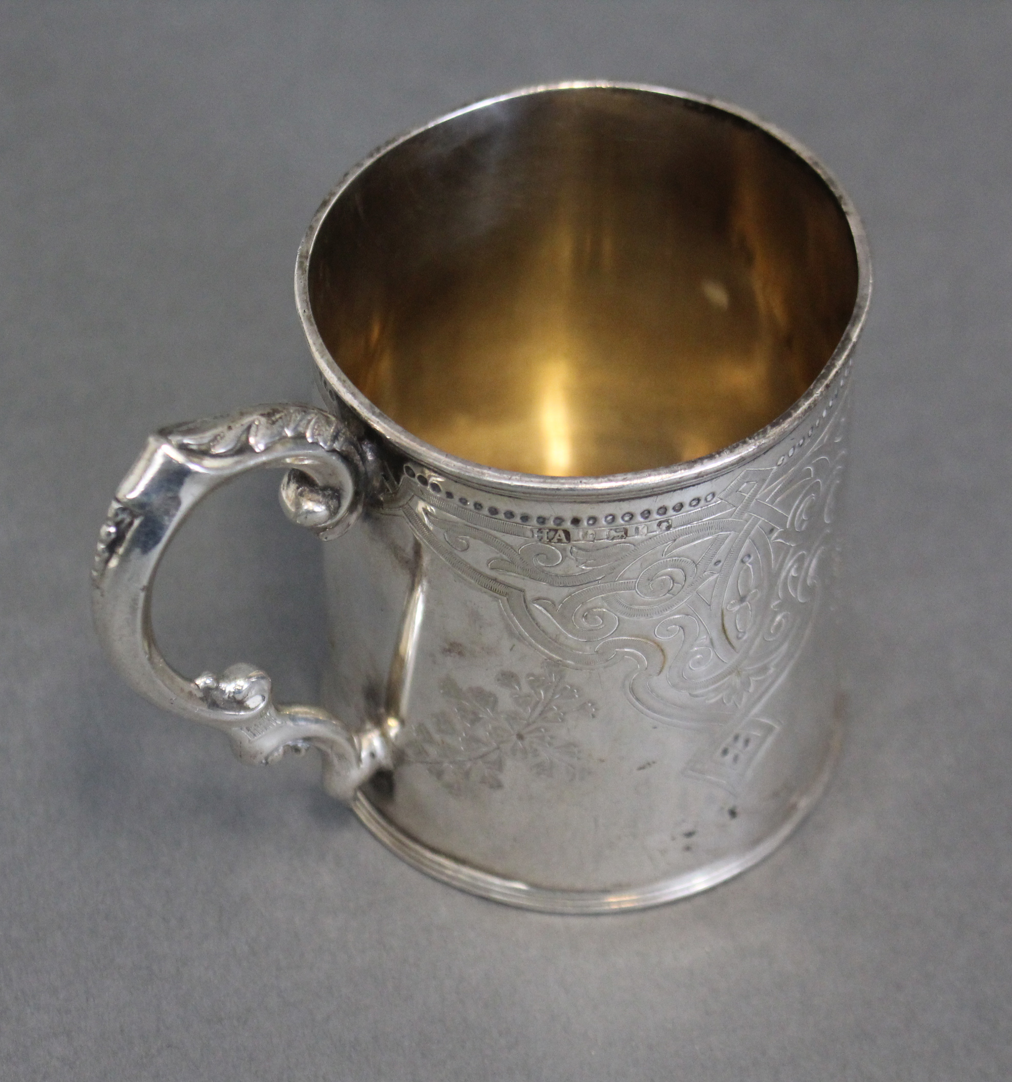 A Victorian silver cylindrical mug with engraved decoration, shaped scroll handle & reeded foot; - Image 3 of 3