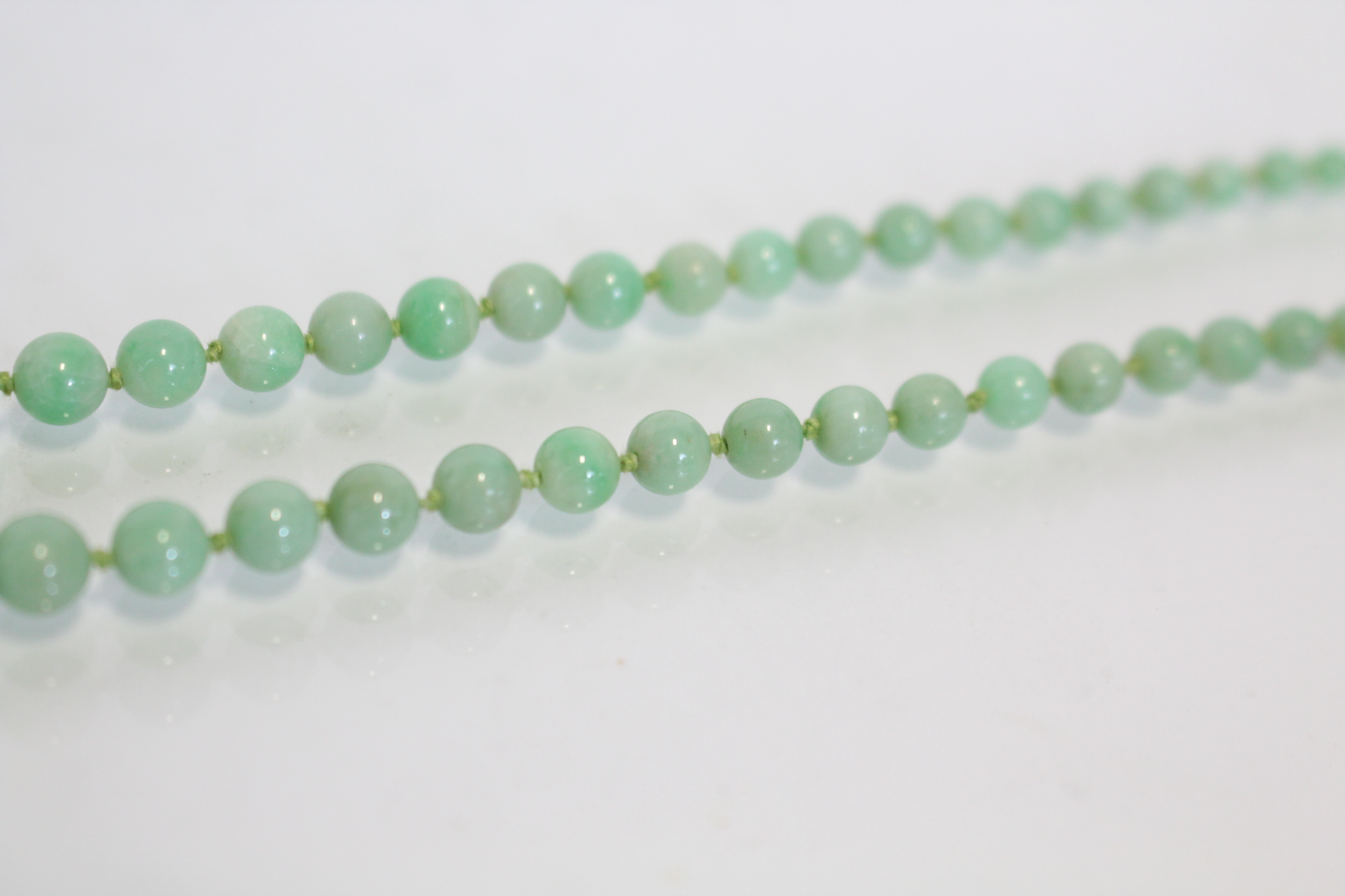 A jade necklace of pale green round graduated beads, the yellow metal pierced oval clasp marked 9ct. - Image 4 of 5