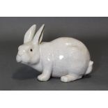 A French faience model of a rabbit, with grey/green “crackle” glaze, painted eyes, incised mark to