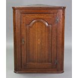 A late 18th century inlaid oak corner cupboard, fitted two shelves enclosed by fielded panel door