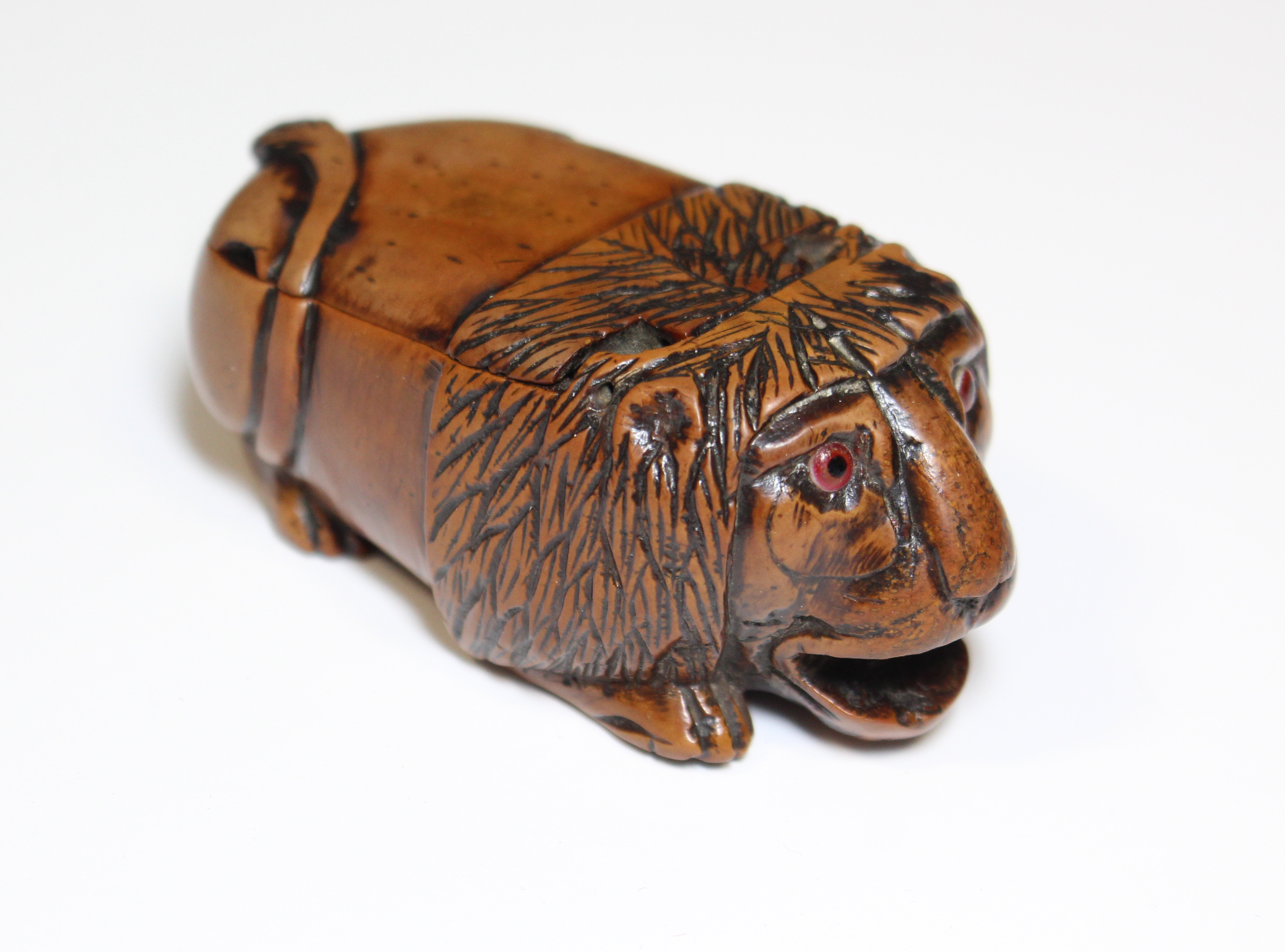 A 19th century coquilla-nut snuff box carved in the form of a crouching lion, with inset glass