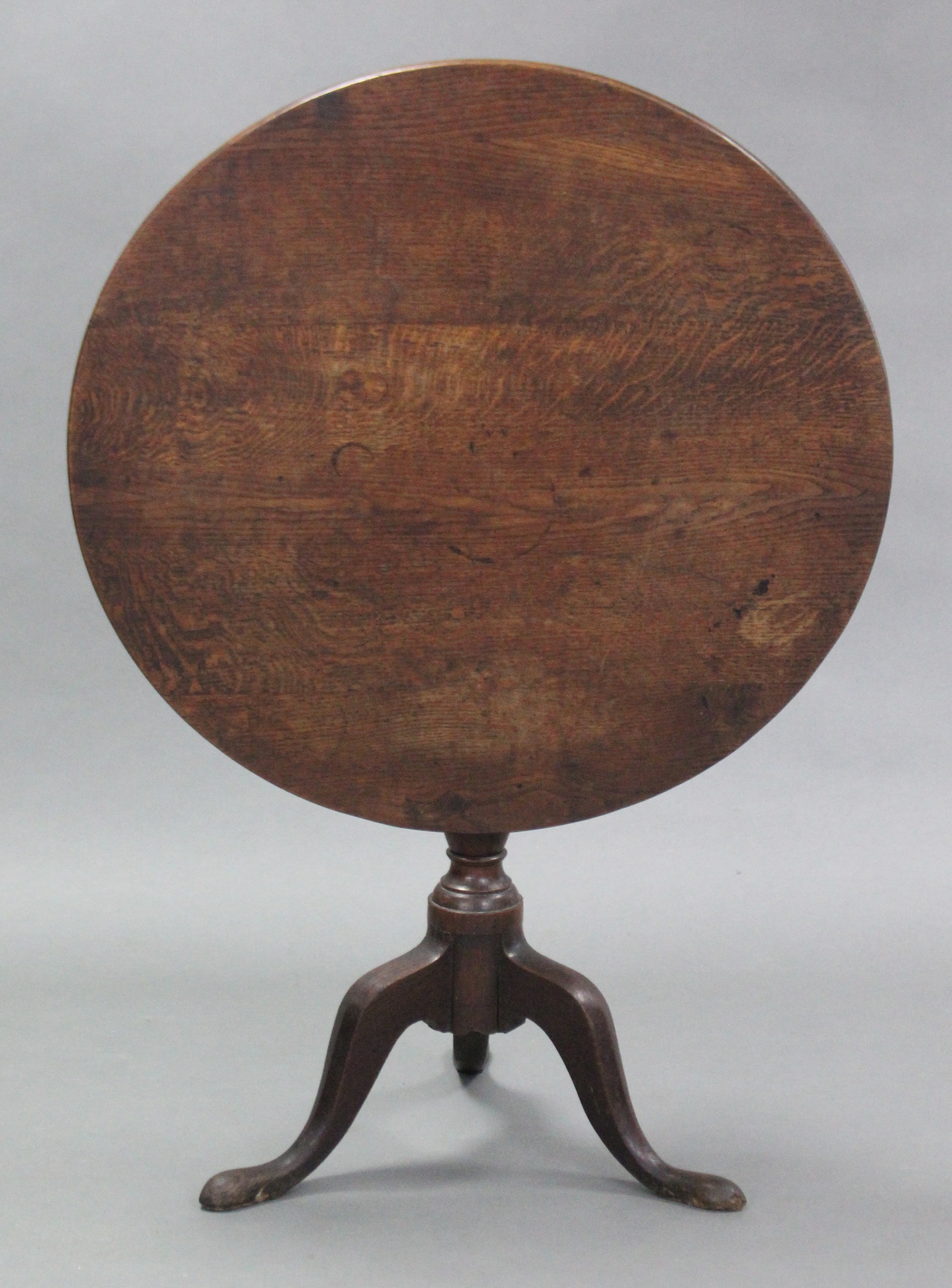 A Georgian oak tripod table with circular top, on vase-turned centre column with cabriole legs & pad