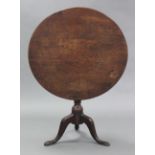 A Georgian oak tripod table with circular top, on vase-turned centre column with cabriole legs & pad