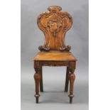 A Victorian oak hall chair with shaped & carved back, on turned tapering front legs (repaired).