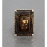 A smokey topaz ring, the large emerald-cut stone set to a cage-work mount, the shank marked: “18KT”;