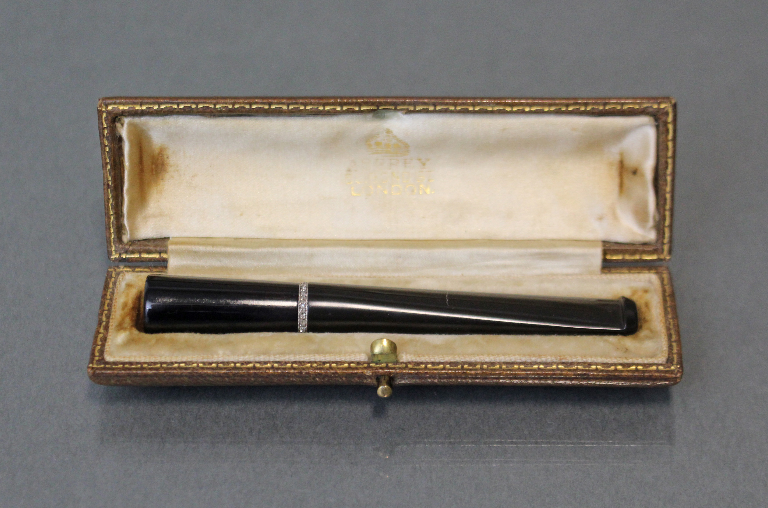 An Asprey diamond-set cigarette holder, the plain sleek black body with narrow white metal band