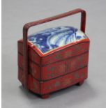 A Japanese lacquered bento box of three stacking tiers, red ground with stylised floral decoration &