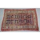 A Persian rug of crimson & ivory ground, the central deep blue panel with geometric designs, in