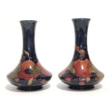 A pair of Moorcroft “Pomegranate” pattern squat round vases with tall narrow necks, blue painted