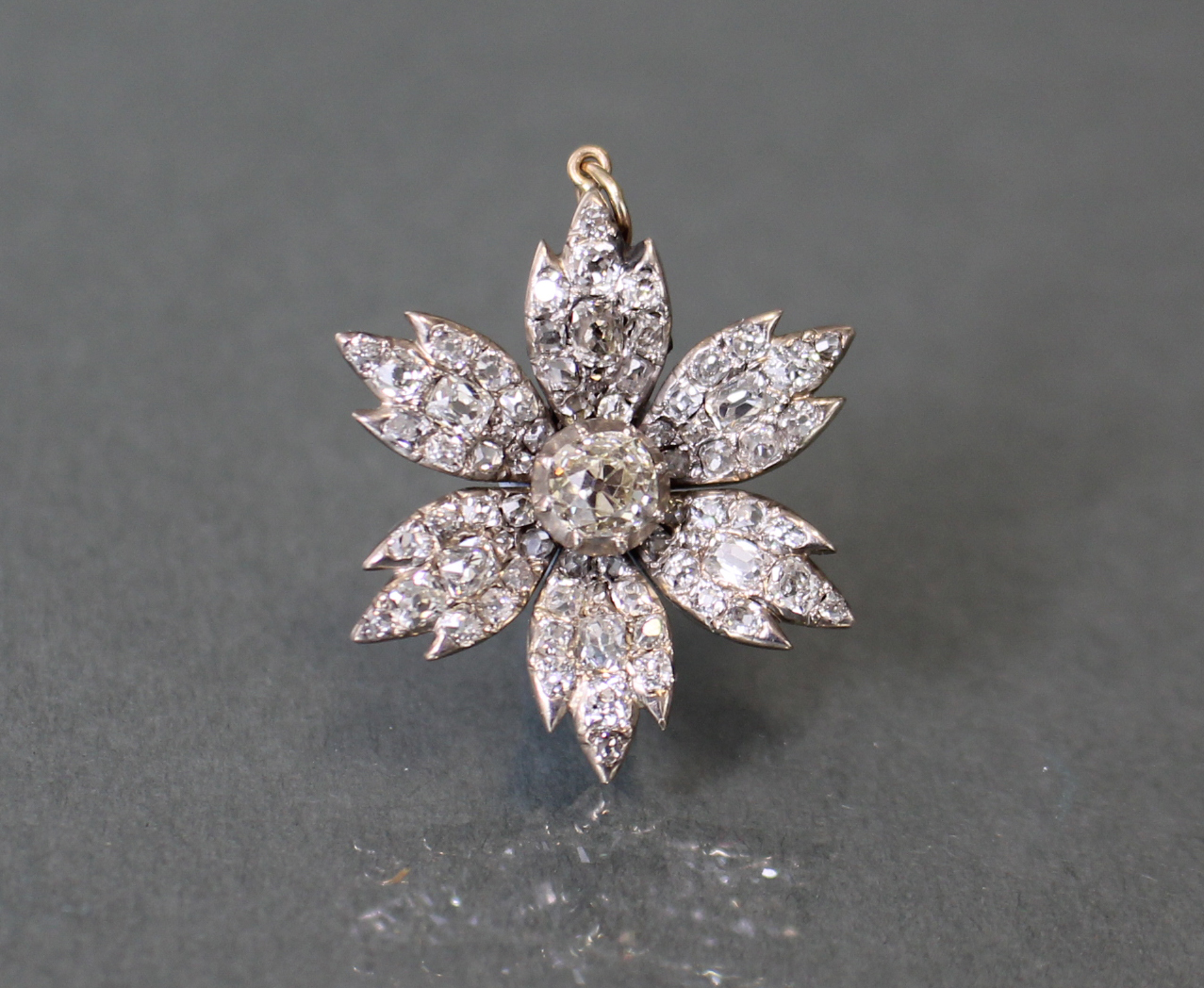 A DIAMOND FLOWER-HEAD PENDANT, the centre stone approximately 0.5 carat, surrounded by six petals