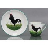 A Wemyss pottery cream-ground teacup & saucer with painted decoration of a cockerel amongst grass;