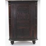 A Victorian 17th century style carved oak standing corner cabinet, the panel door decorated with