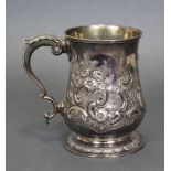 A GEORGE III SILVER TANKARD, the baluster body with embossed decoration of leaf scrolls around a