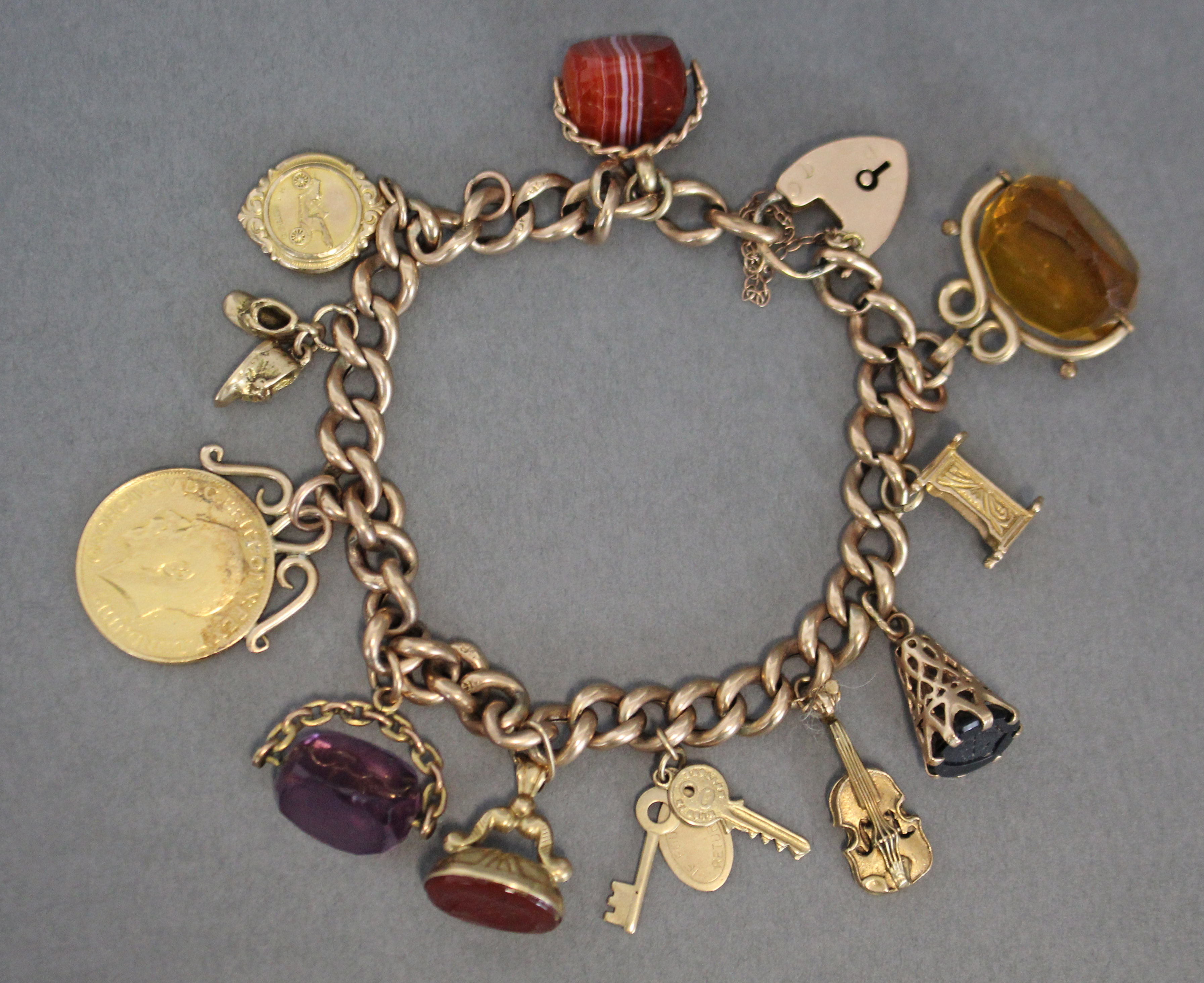 A 9ct. gold curb-link charm bracelet with padlock clasp & safety chain, a pendant George V sovereign