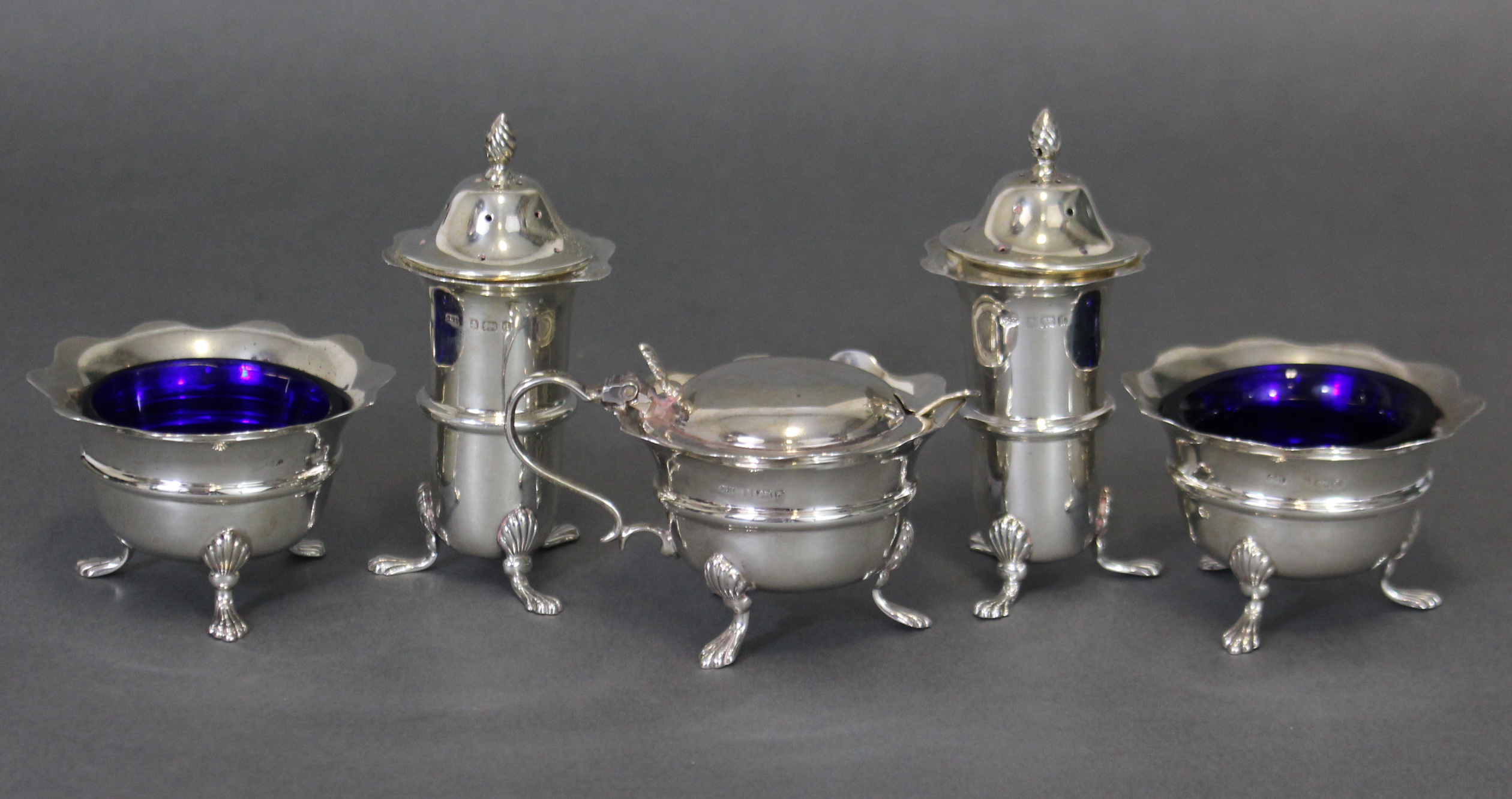 An Edwardian silver five-piece condiment set, each of round shape with card-cut rims & on three