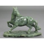 A LARGE CARVED GREEN JADE-ITE MODEL OF A HORSE, its right leg raised & head turned to the left, with